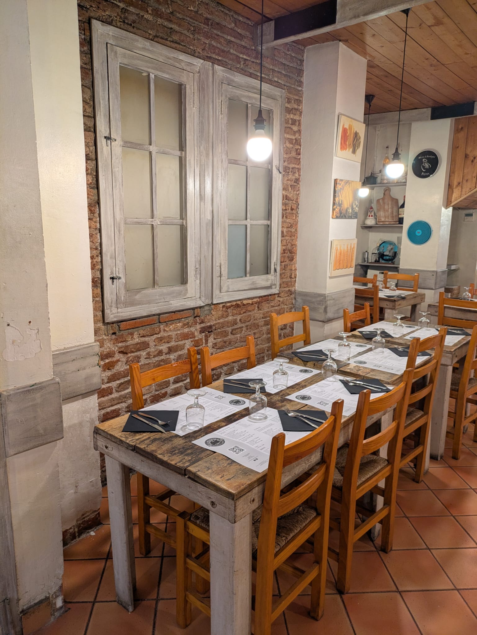 Sala amb paret de maó vist i finestres de fusta — La Pentola